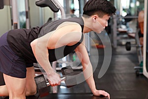 Asian chinese man in gym ï¼ŒFitness young man in the gym doing exercises with dumbbells