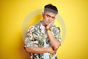 Asian chinese man on holiday wearing summer shirt over isolated yellow background thinking looking tired and bored with depression