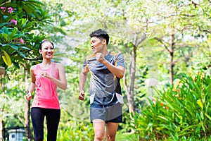 Asian Chinese man and woman jogging in city park