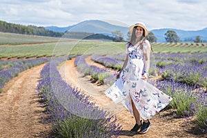 Portrait of beautiful romantic woman floral dress and stylish hat in field of lavender flowers
