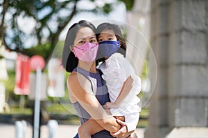 Asian chinese mother and child wearing mask outdoors in park garden