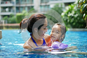 Asian Chinese Mother and Daughter bonding in the swimming pool smiling happy