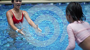 asian Chinese mother and daughter enjoying at the pool with mother catching daughter