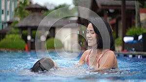 Asian Chinese mother and daughter learning how to swim at the pool frontal view happy