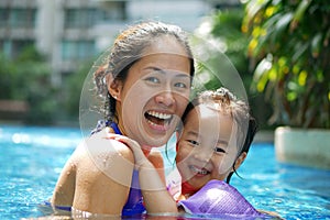 Asian Chinese Mother and Daughter smiling and bonding in the swimming pool smiling happy