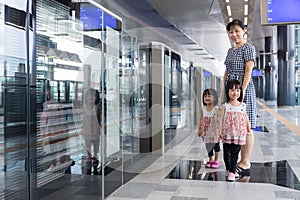 Asian Chinese mother and daughters waiting for transit at station