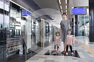 Asian Chinese mother and daughters waiting for transit at station