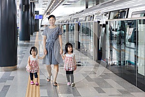 Asian Chinese mother and daughters waiting for transit at station