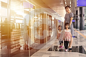 Asian Chinese mother and daughters waiting for transit at station