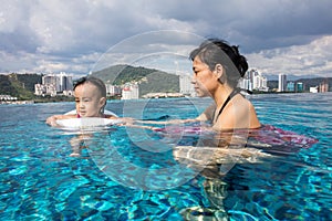 Asian Chinese mother and daugther playing at swimming pool