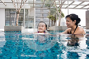 Asian Chinese mother and daugther playing at swimming pool photo
