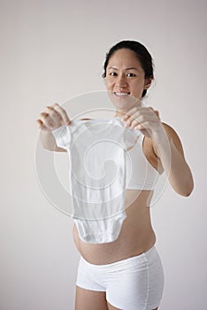 Asian Chinese new pregnant mum holding up an infant clothing