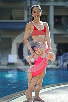 Asian Chinese parent and child posing at a swimming pool