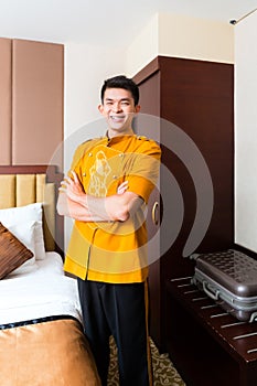 Asian Chinese porter bringing suitcase to luxury hotel room