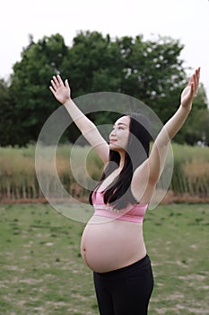 Asian Chinese pregnant woman in yoga dress embrace hug nature have fresh air enjoy peaceful life relax meditation in forest garden