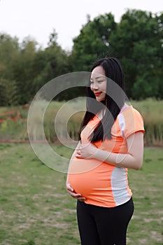 Asian Chinese pregnant woman in yoga dress embrace hug nature have fresh air enjoy peaceful life relax meditation in forest garden