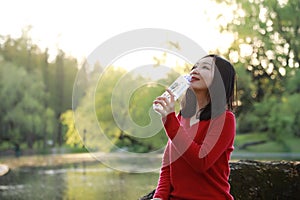 Asian Chinese pretty woman smiling and drinking water in nature in spring outdoor