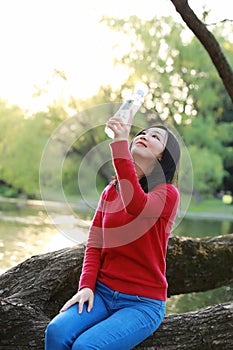 Asian Chinese pretty woman smiling and drinking water in nature in spring outdoor