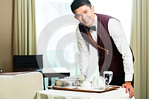 Asian Chinese room service waiter serving food in hotel photo