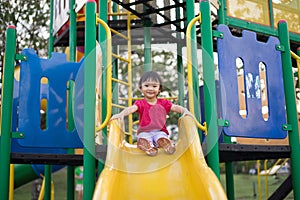 Asian Chinese two-year old girl on a slide in the playground