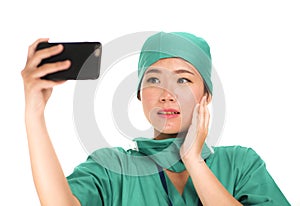 Asian Chinese woman as successful taking selfie on hand phone - young beautiful and happy medicine doctor or hospital nurse taking
