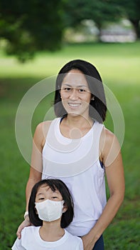 Asian chinese woman with daughter in mask in outdoor garden