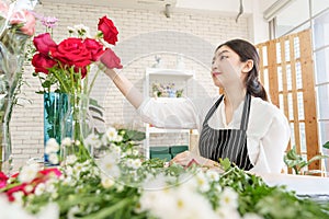 Asian Chinese woman florist making beautiful bouquet of red roses