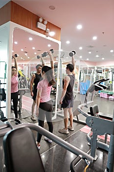 Asian chinese woman in gym lifting weights