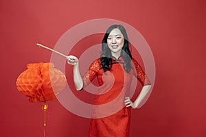 Asian chinese woman in red cheongsam or qipao holding denglong the paper lantern to wish the good luck and prosperity in Chinese