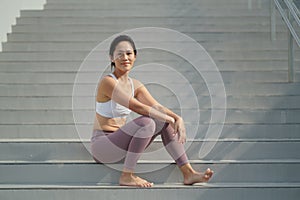 Asian Chinese Woman resting at the stair case in sporting attire smiling