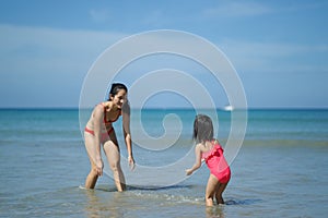 Asian chinese woman spending time playing with daughter at the beach