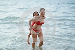 Asian chinese woman spending time playing with daughter at the beach