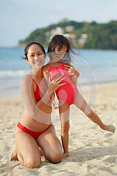 Asian chinese woman spending time playing with daughter at the beach