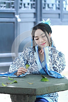 Asian Chinese woman in traditional Blue and white Hanfu dress, kill time in a famous garden