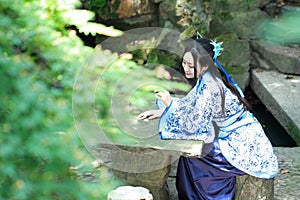 Asian Chinese woman in traditional Blue and white Hanfu dress, play in a famous garden