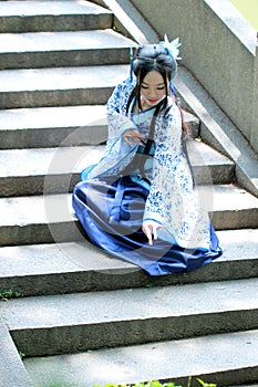 Asian Chinese woman in traditional Blue and white Hanfu dress, play in a famous garden