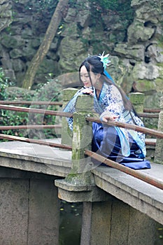 Asian Chinese woman in traditional Blue and white Hanfu dress, play in a famous garden Climb on the bent bridge