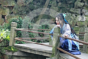 Asian Chinese woman in traditional Blue and white Hanfu dress, play in a famous garden Climb on the bent bridge