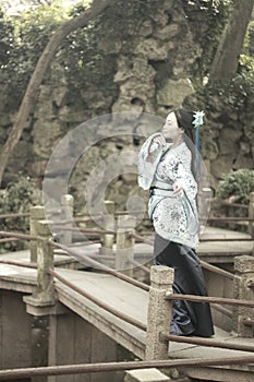 Asian Chinese woman in traditional Blue and white Hanfu dress, play in a famous garden on crooked Bridge