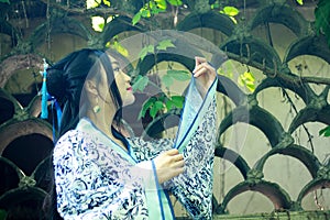 Asian Chinese woman in traditional Blue and white Hanfu dress, play in a famous garden near wall