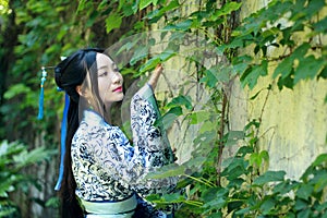 Asian Chinese woman in traditional Blue and white Hanfu dress, play in a famous garden near wall