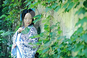 Asian Chinese woman in traditional Blue and white Hanfu dress, play in a famous garden near wall