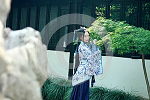 Asian Chinese woman in traditional Blue and white Hanfu dress, play in a famous garden near windows