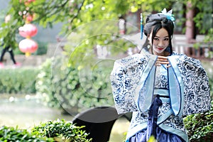 Asian Chinese woman in traditional Blue and white Hanfu dress, play in a famous garden ,sit on an ancient stone chair