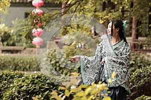 Asian Chinese woman in traditional Blue and white Hanfu dress, play in a famous garden ,sit on an ancient stone chair