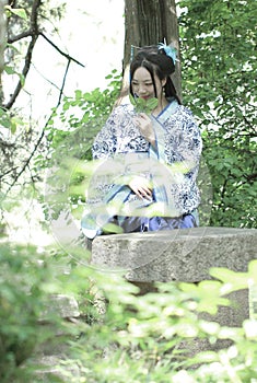 Asian Chinese woman in traditional Blue and white Hanfu dress, play in a famous garden ,sit on an ancient stone chair