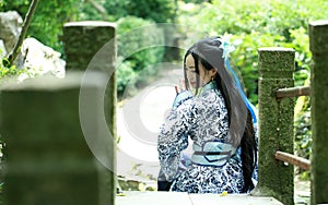 Asian Chinese woman in traditional Blue and white Hanfu dress, play in a famous garden ,Sit on the bridge