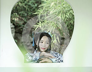 Asian Chinese woman in traditional Blue and white Hanfu dress, play in a famous garden ,Stand in front of the window