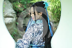 Asian Chinese woman in traditional Blue and white Hanfu dress, play in a famous garden ,Stand in front of the window