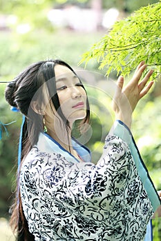 Asian Chinese woman in traditional Blue and white Hanfu dress, play in a famous garden ,Stand under the maple tree
